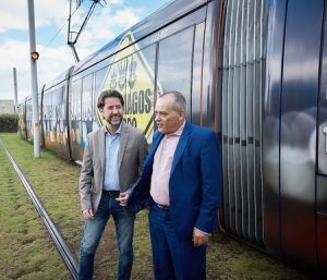 Carlos Alonso, presidente de Metrotenerife, y Efraín Medina, vicepresidente económico del Cabildo Insular, junto al tranvía rotulado con la imagen de la campaña navideña. 