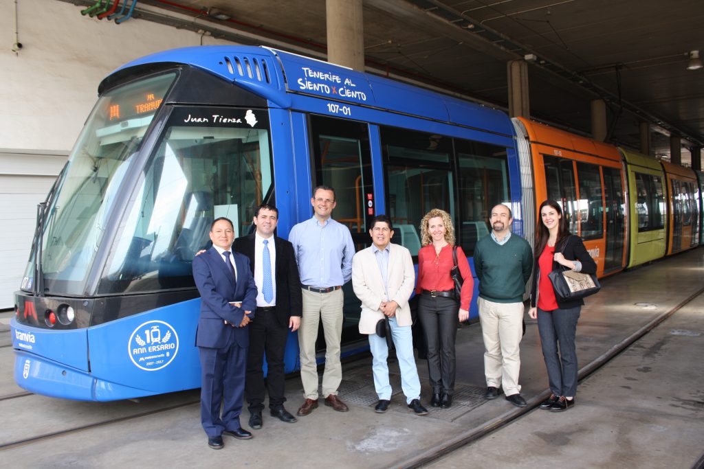 Autoridades de Metrotenerife y de las delegaciones de Colombia y Per&uacute; posan en cocheras, delante de un tranv&iacute;a