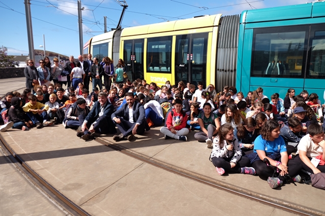 Autoridades y escolares en la zona de cocheras junto a un tranvía.